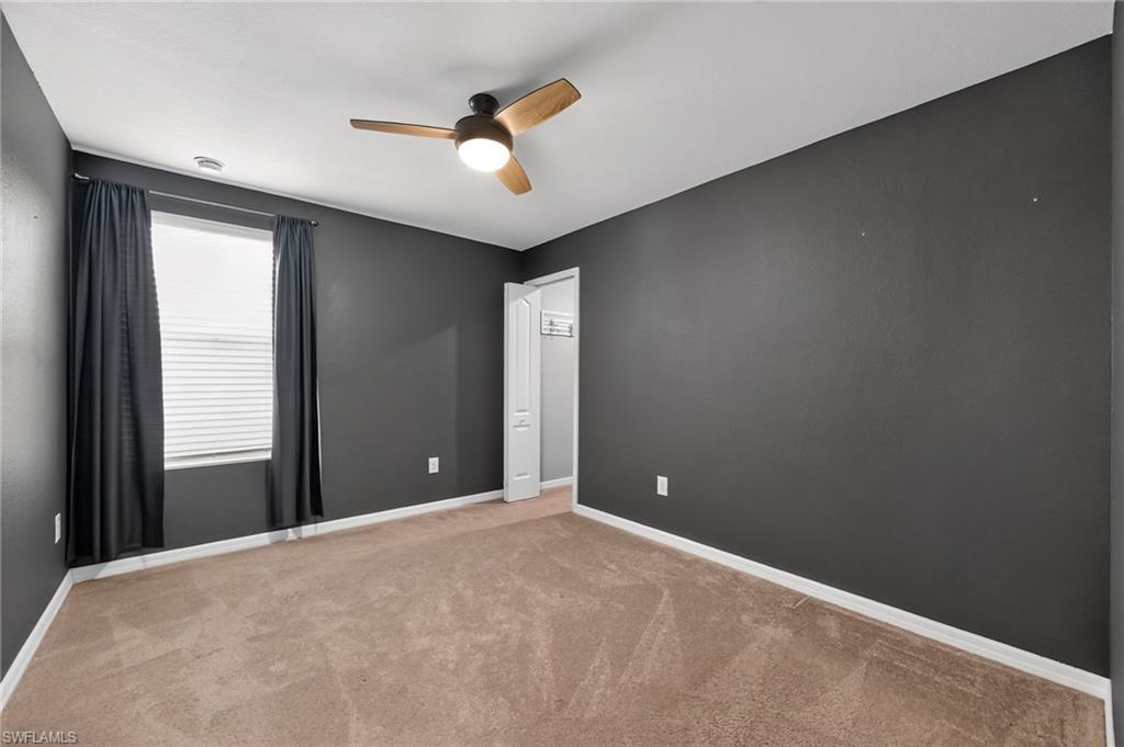 Ceiling fan with light fixture, carpeted flooring, window with blinds, and painted walls