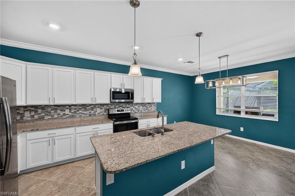 White shaker cabinetry, mosaic tile backsplash, stainless steel appliances, granite island, and tile flooring