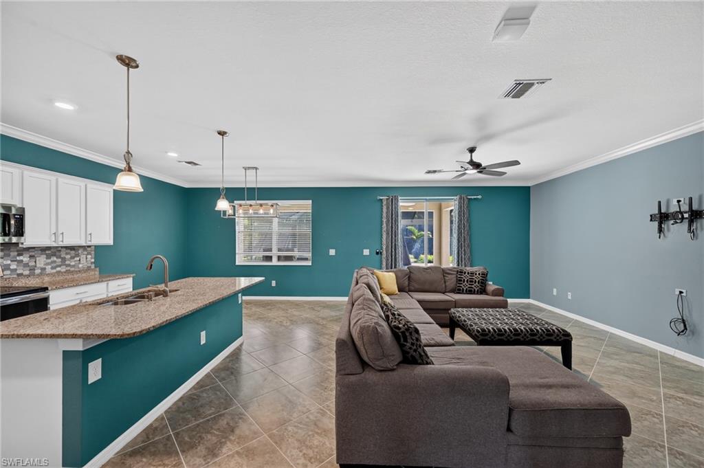 Open-concept living area with tile flooring and crown molding