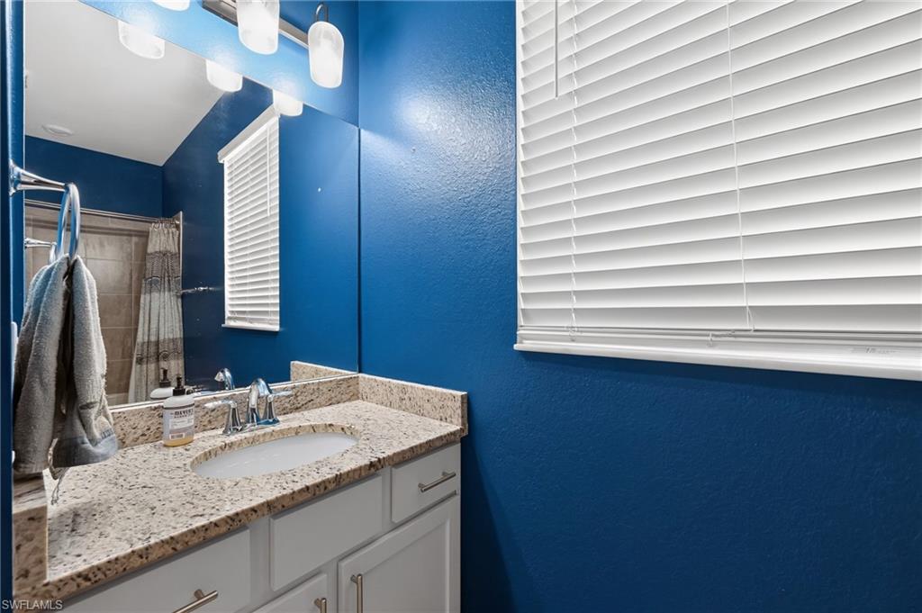 White vanity with brushed nickel hardware, granite-style countertop, undermount sink, and chrome faucet