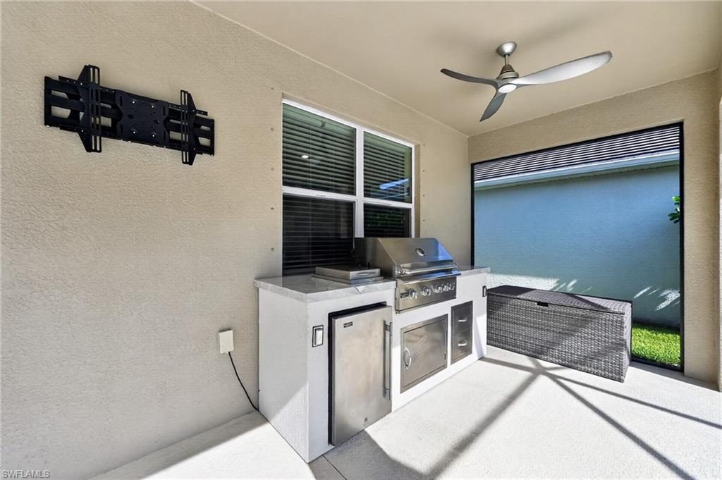 Outdoor kitchen featuring a built-in grill, under-counter refrigerator, stainless steel cabinetry, and a countertop