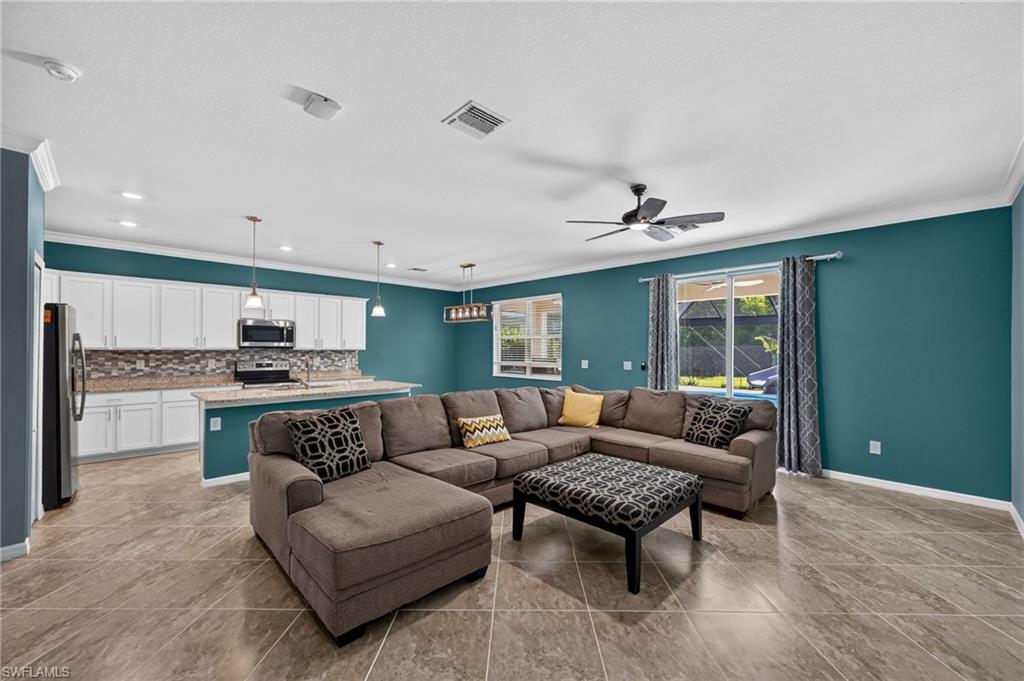 Open concept living area featuring tile flooring, white shaker cabinetry, a tile backsplash, and a breakfast bar
