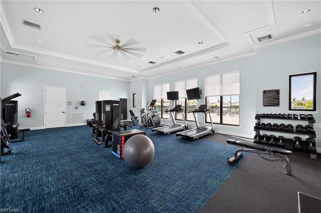 State-of-the-art fitness facility featuring multiple treadmills, a comprehensive dumbbell rack with organized weight storage, exercise equipment including a stability ball, blue tile flooring throughout, and abundant natural light from expansive windows