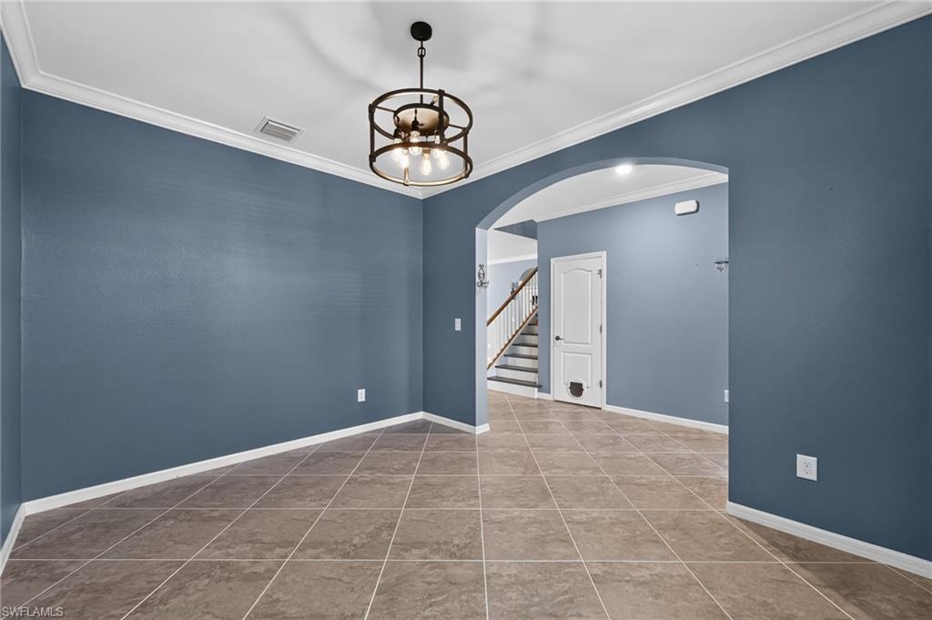 Spacious open-concept dining area showcasing diagonal tile flooring, crisp white crown molding, and soft blue walls