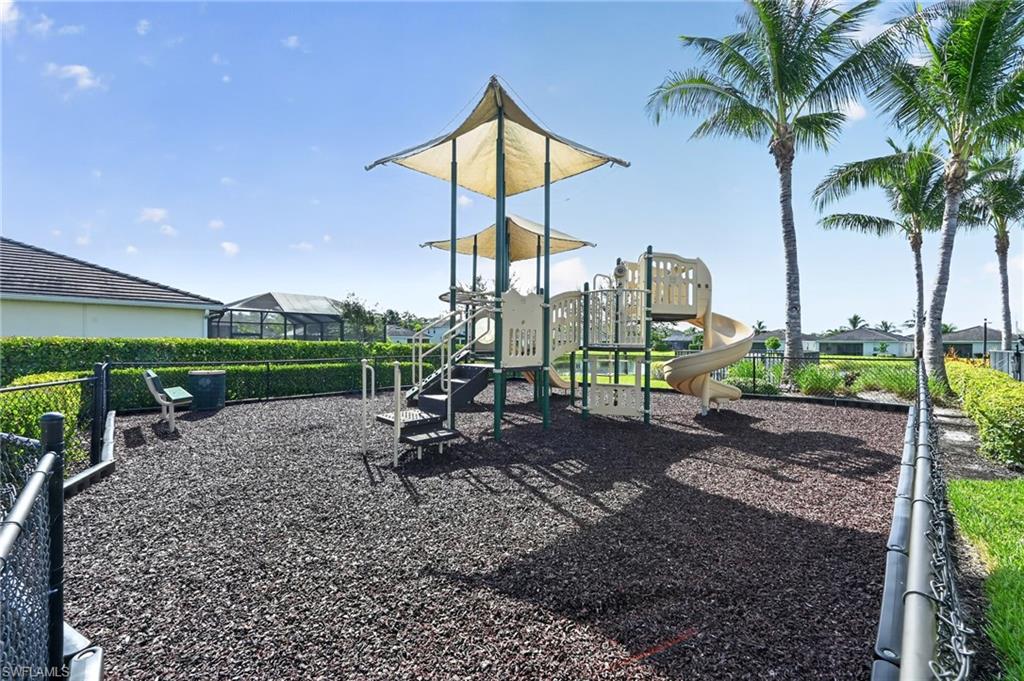 Community playground featuring a multi-level play structure with integrated slide, dual shade canopies, and rubberized safety surfacing
