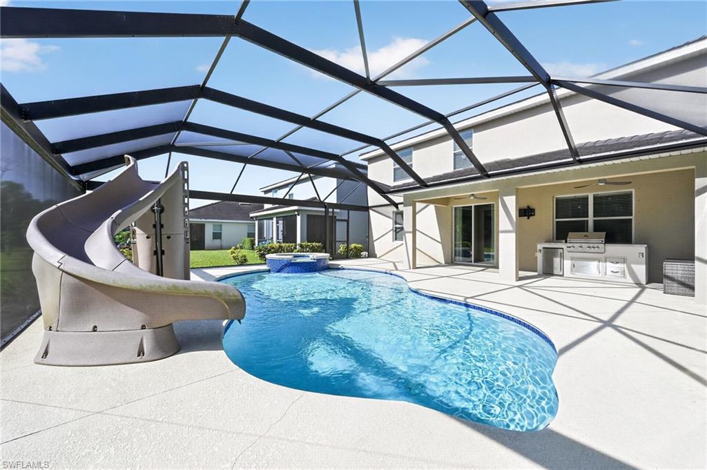Gated entrance with multiple access lanes, featuring manicured landscaping and mature palm trees
