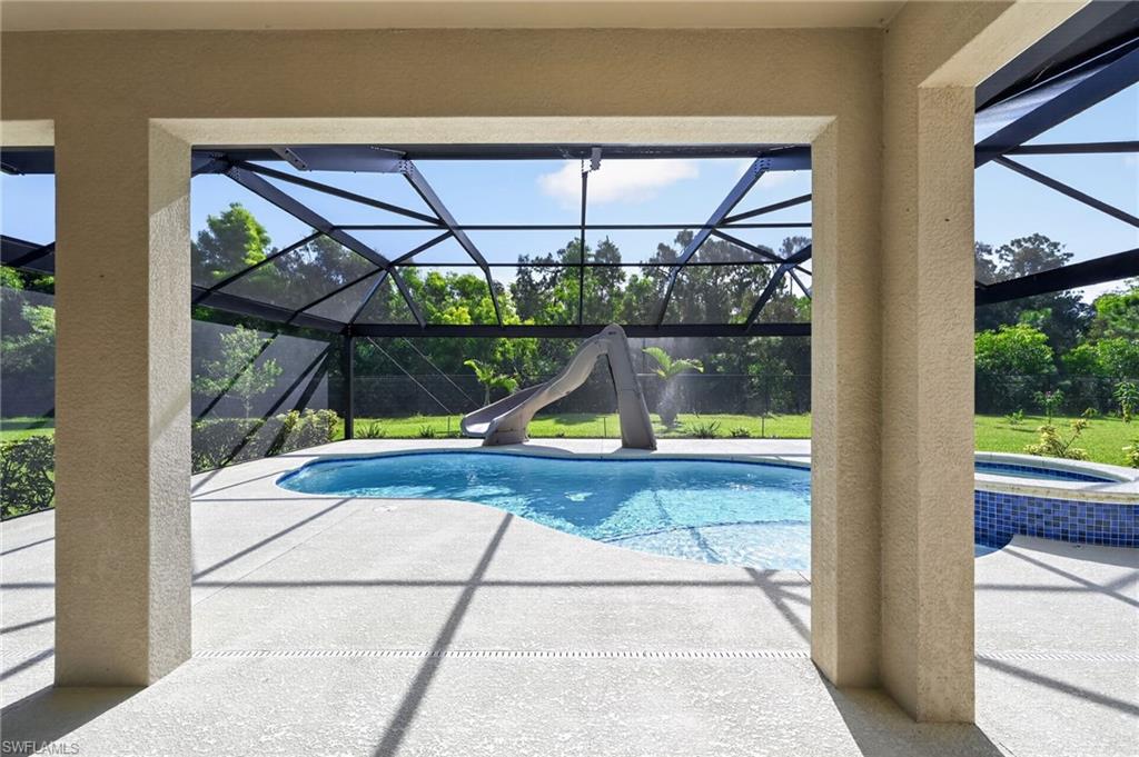Resort-style pool area with crystal-clear waters, expansive sun deck, and a screened enclosure featuring black metal framework