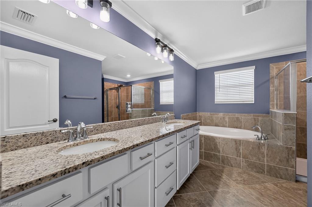 Spa-inspired master bathroom featuring dual vanities with white cabinetry, granite countertops, and polished nickel hardware