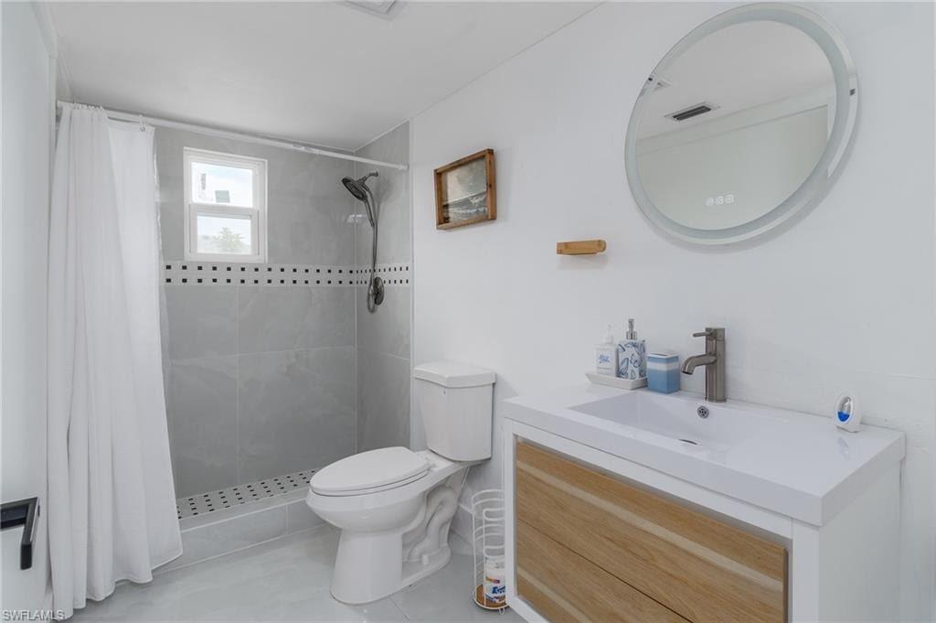 Shower with light gray tile surround, decorative accent band, and window