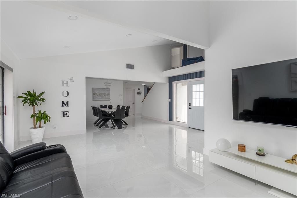 Open-concept living area featuring polished white flooring, recessed ceiling lighting, and wall-mounted flat-screen television