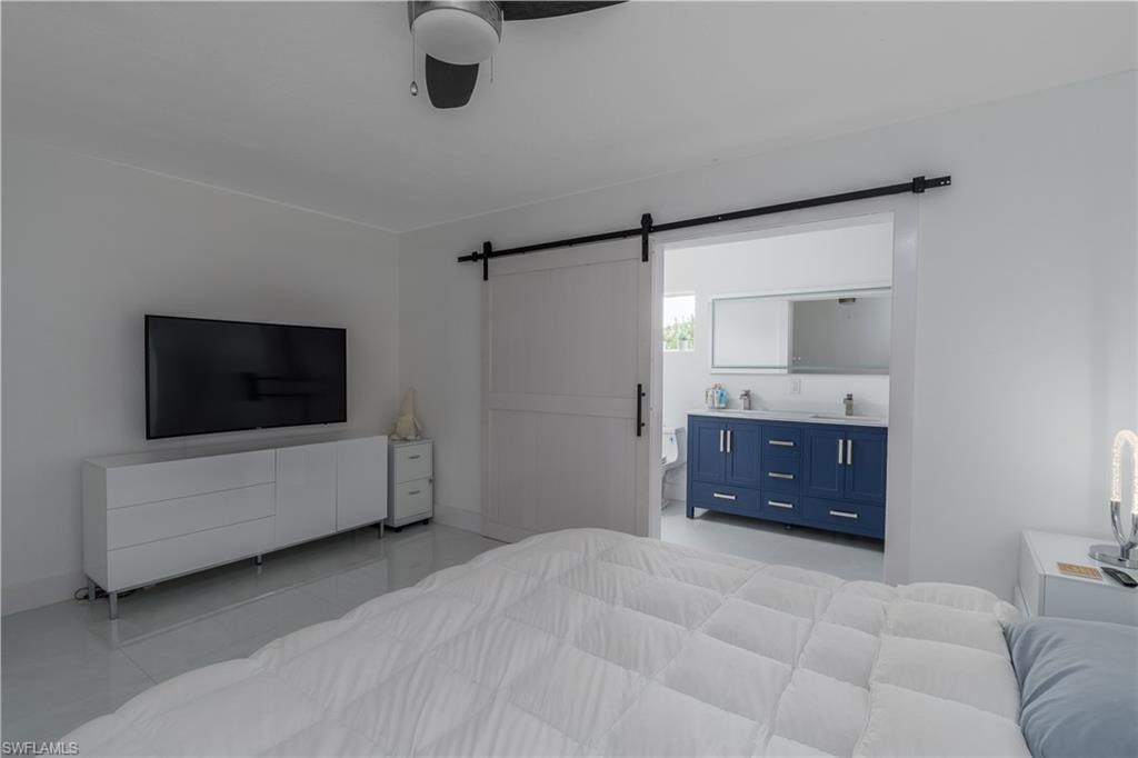White sliding barn door, white walls, ceiling fan, and white tile flooring