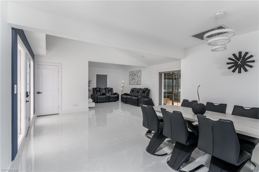 Open-concept interior featuring high gloss tile flooring, white walls, and a modern tiered chandelier