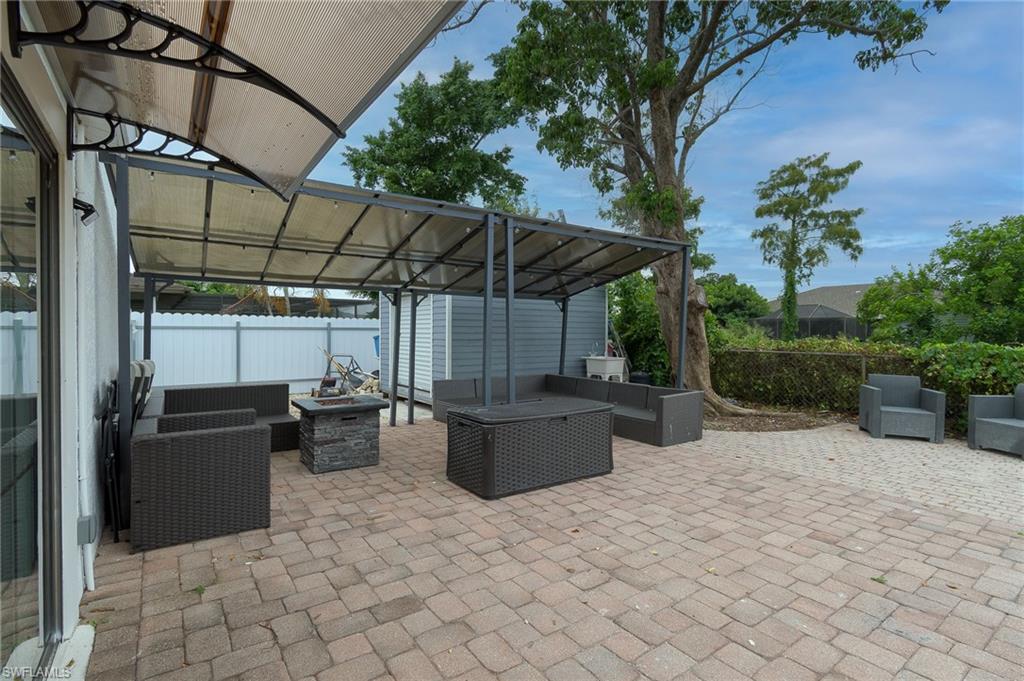 Paver patio featuring a covered pergola, additional awning, and a stone-finish fire pit