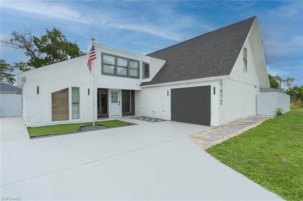 White exterior with dark-framed windows and a dark garage door