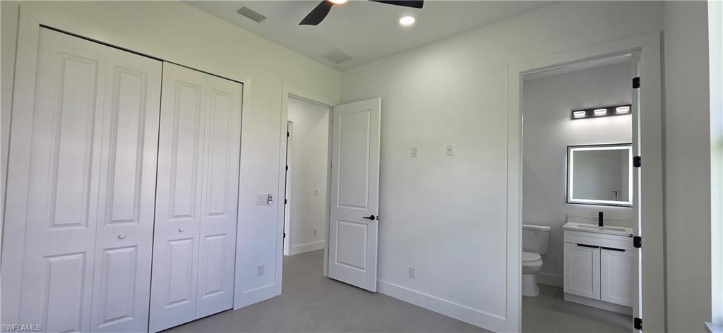 Recessed lighting, ceiling fan, white bi-fold closet doors, white vanity with black hardware, and backlit mirror
