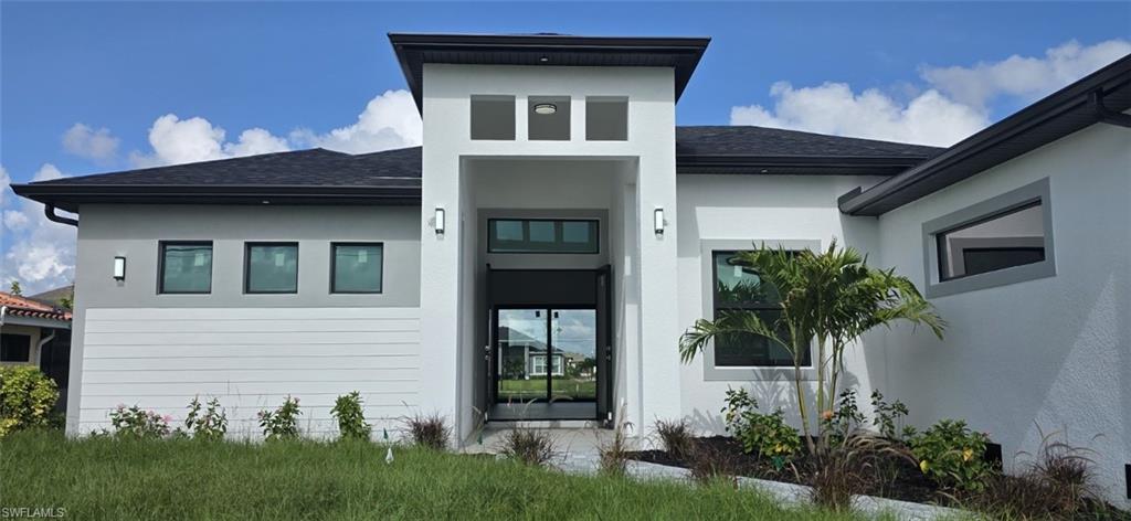 Contemporary-style exterior with a flat roofline, stucco finish, and a prominent entryway featuring a transom window