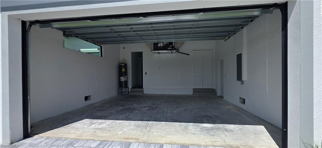 Spacious garage with concrete flooring, automatic garage door opener, and a built-in water heater