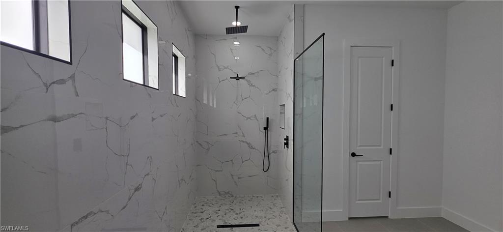 Walk-in shower with full-height tile surround, rain shower head, matte black fixtures, and recessed niche