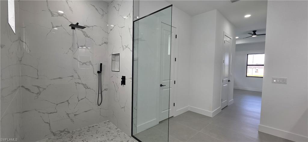 Walk-in shower with full-height tile surround, matte black shower fixtures, and a glass enclosure