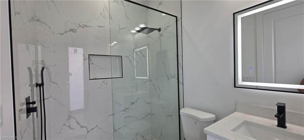 Glass-enclosed shower with a recessed niche, rain shower head, and matte black fixtures