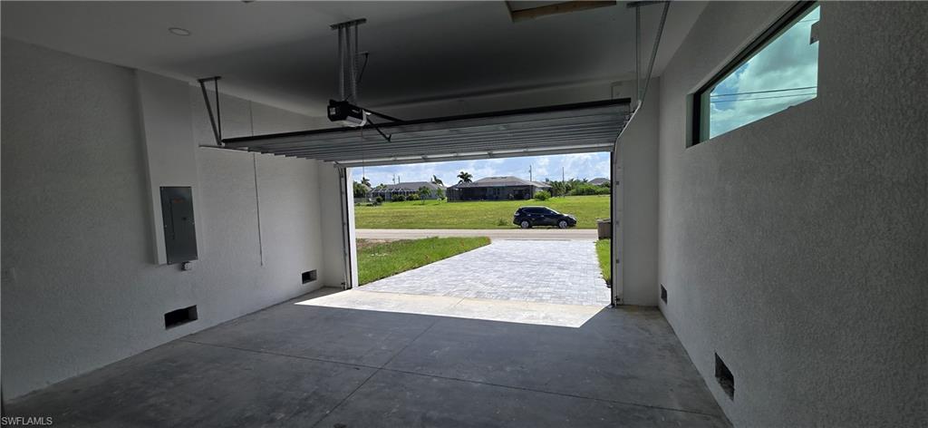 Attached garage with an automatic door opener, concrete flooring, and a high horizontal window