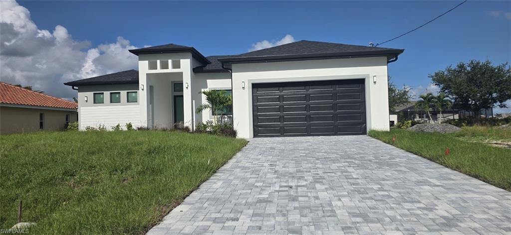 Contemporary exterior with white stucco finish, dark gray garage door, and a paver driveway
