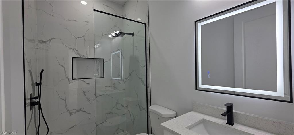Walk-in shower with full-height marble-style tile surround and integrated niche