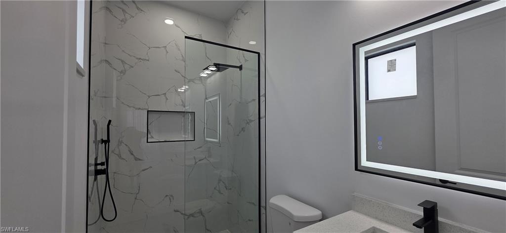 Walk-in shower with a glass enclosure, black-finish fixtures, and a recessed niche