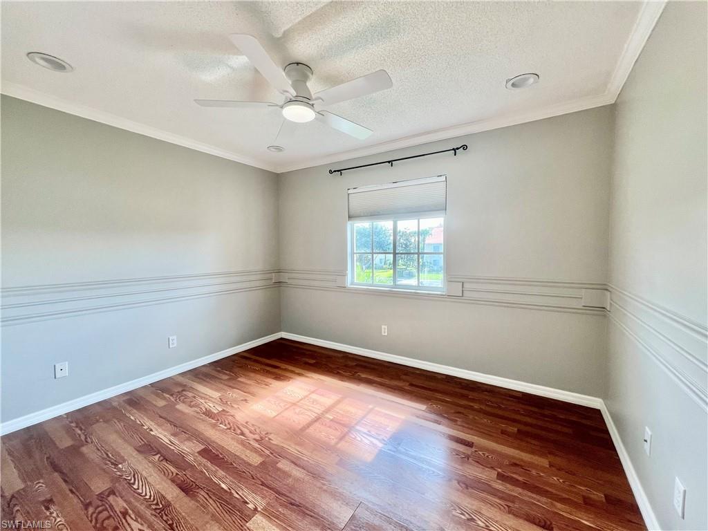 Guest Empty room featuring wood finished floors, a ceiling fan, ornamental molding, baseboards, and a textured ceiling