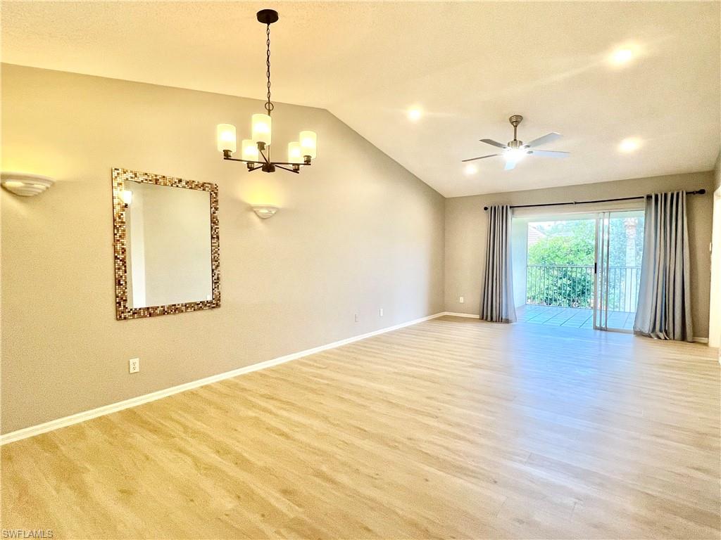 Unfurnished room featuring lofted ceiling, light wood-style flooring, baseboards, a chandelier, and a ceiling fan