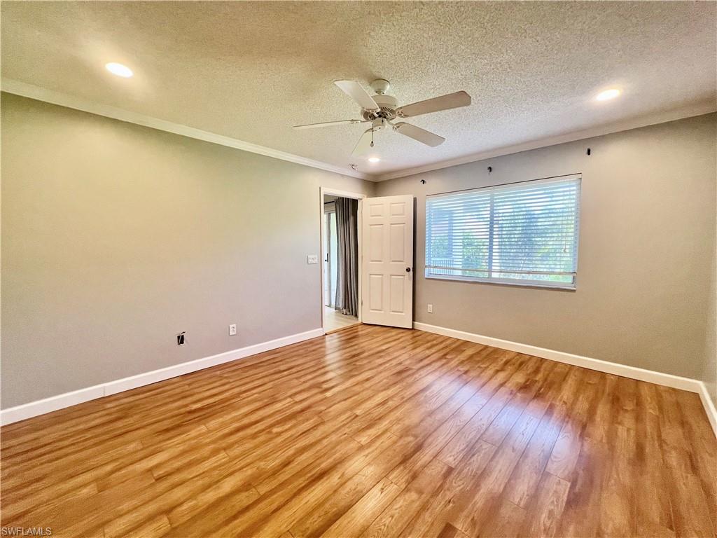 Master Empty room featuring a textured ceiling, light wood-style floors, baseboards, a ceiling fan, and crown molding