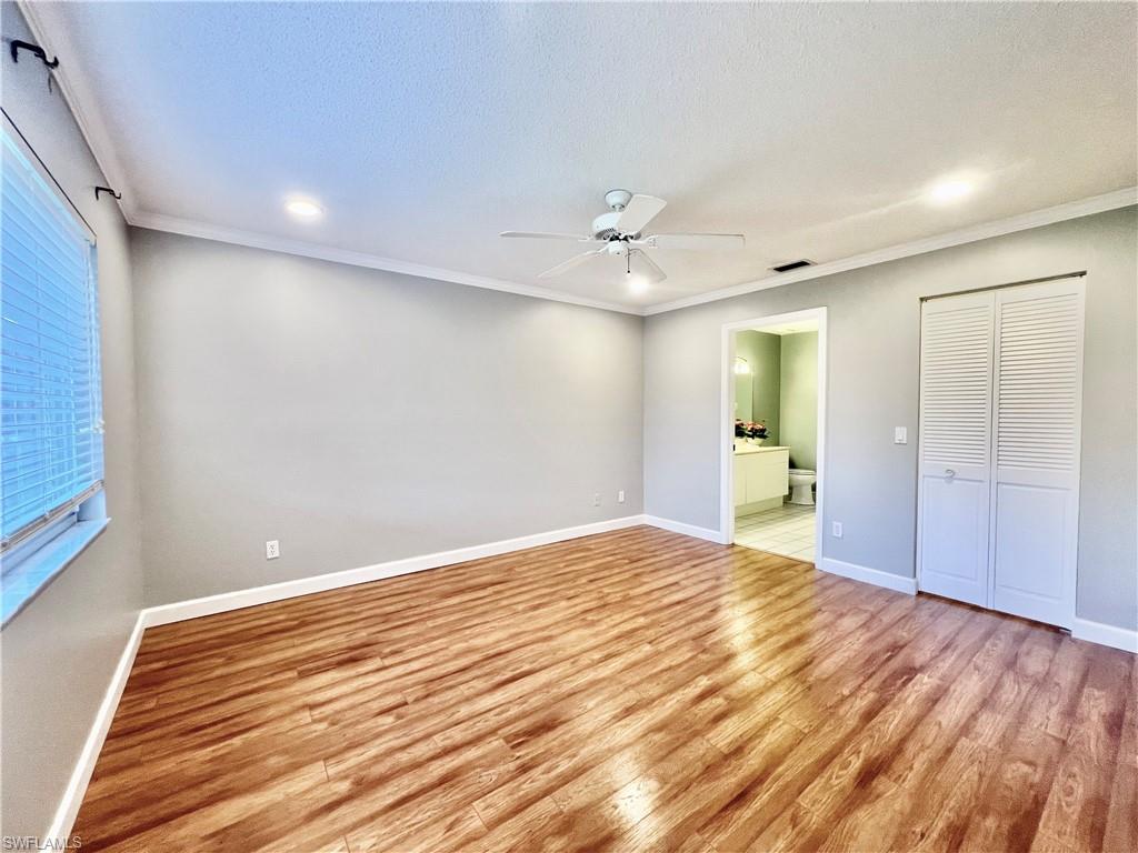 Master Unfurnished bedroom with light wood-type flooring, baseboards, crown molding, connected bathroom, and recessed lighting