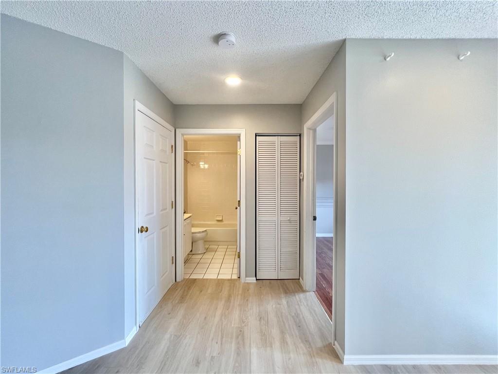 Guest Corridor with light wood-type flooring, baseboards, and a textured ceiling