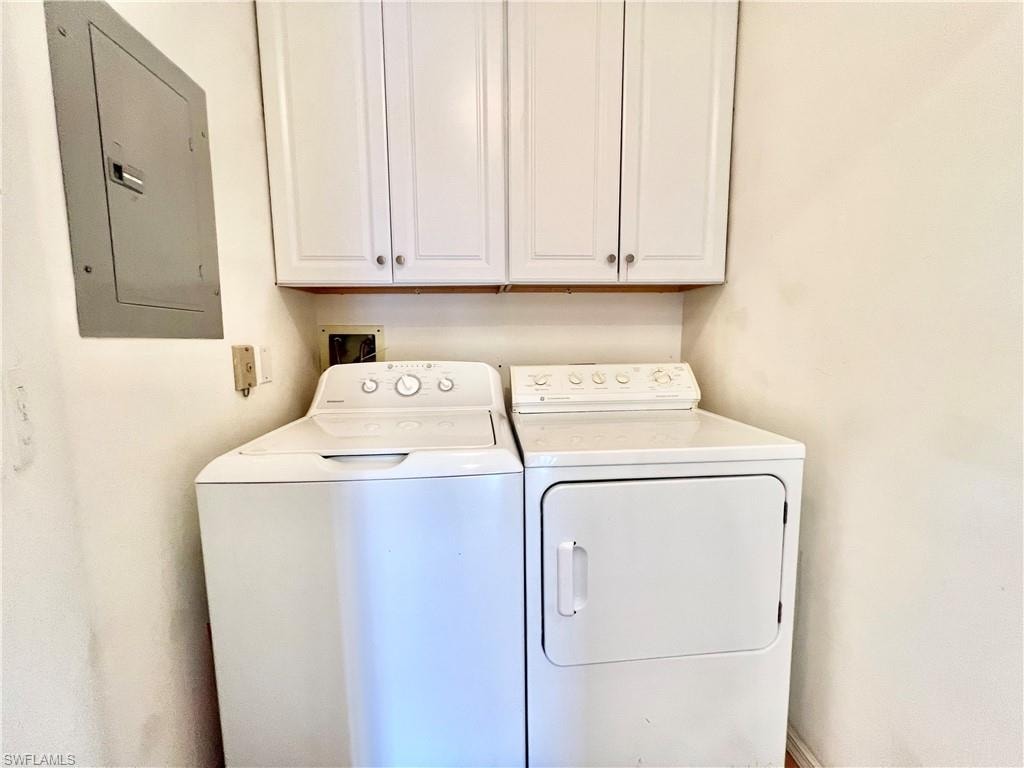 Laundry area featuring electric panel, cabinet space, and washing machine and clothes dryer