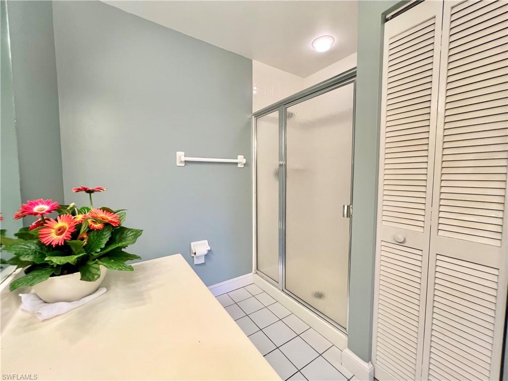 Master Bathroom featuring a closet, tile patterned floors, a stall shower, and baseboards