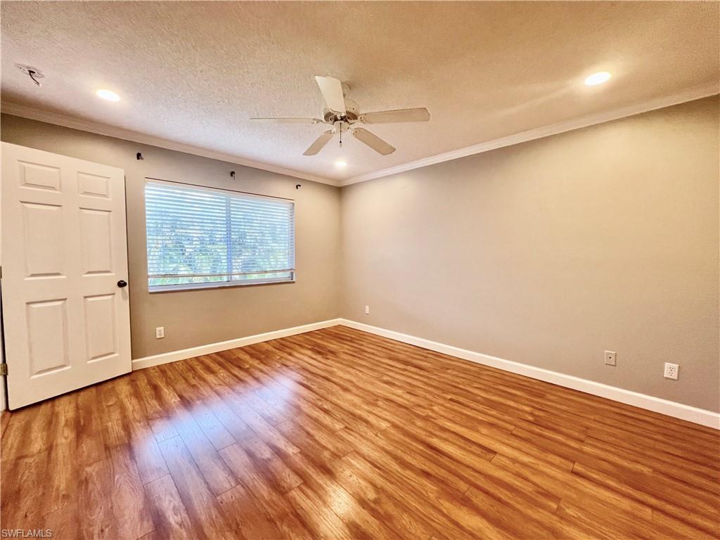 Master Unfurnished room with wood finished floors, ornamental molding, baseboards, ceiling fan, and a textured ceiling