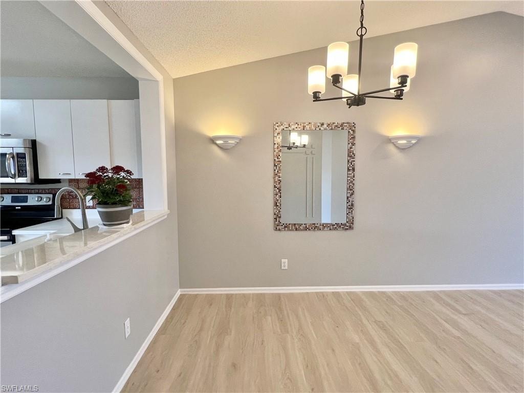Unfurnished dining area with a chandelier, light wood-style floors, baseboards, and a sink