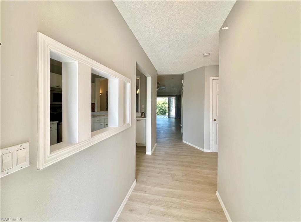 Entry Hallway with light wood-style floors, a textured ceiling, and baseboards