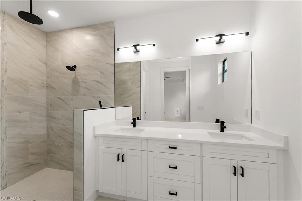 Primary bathroom with a large walk in shower with multiple shower heads and a washdown just behind the short wall. Dual sinks, quartz countertops, soft close cabinets, and a large mirror with plenty of great lighting.