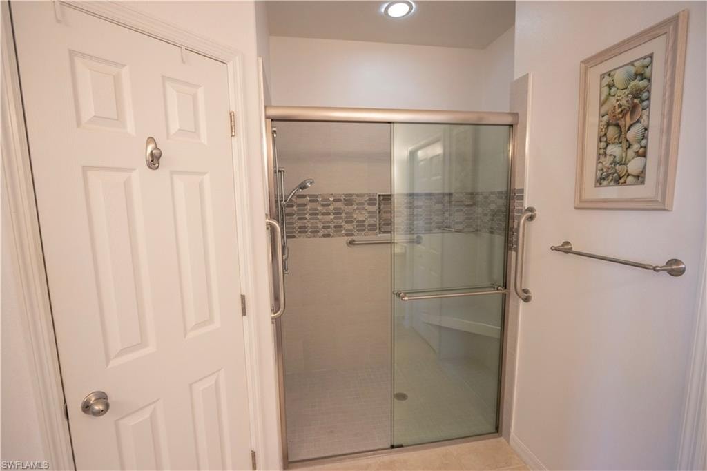 Shower enclosure with sliding glass doors, built-in bench, and decorative tile accent band