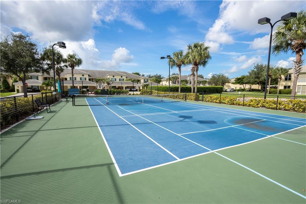 Tennis court with blue and green surfacing, black fencing, and integrated lighting