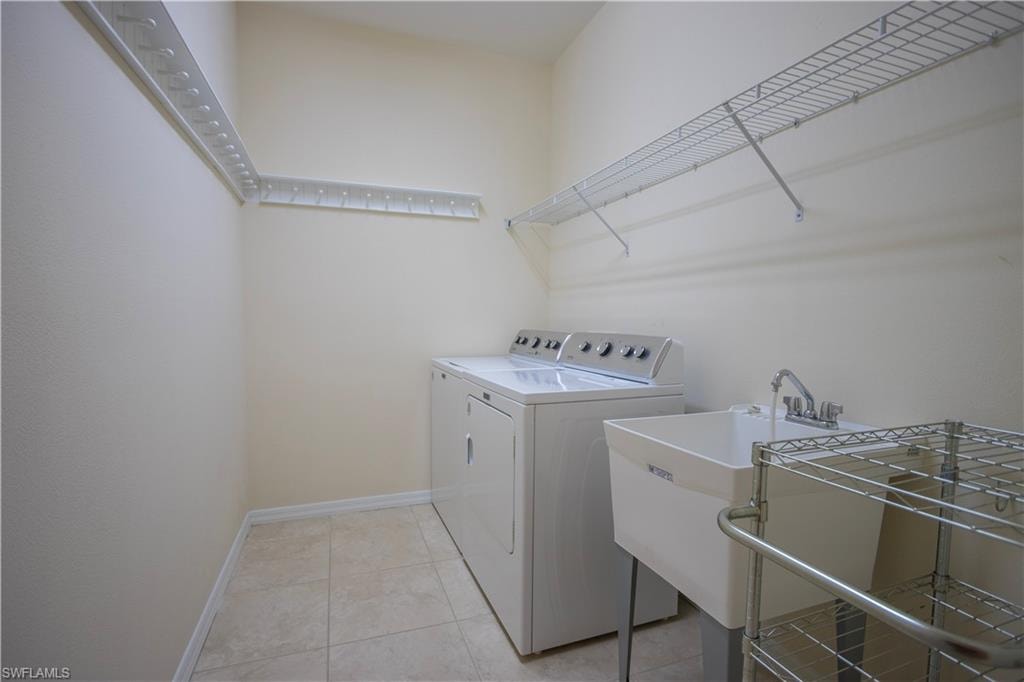 Laundry area featuring tile flooring, a utility sink with a chrome faucet, and ample wire shelving