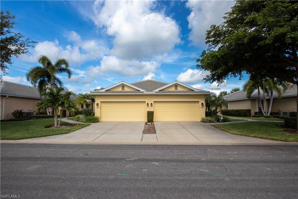 Yellow stucco exterior with a gray shingle roof and prominent gables