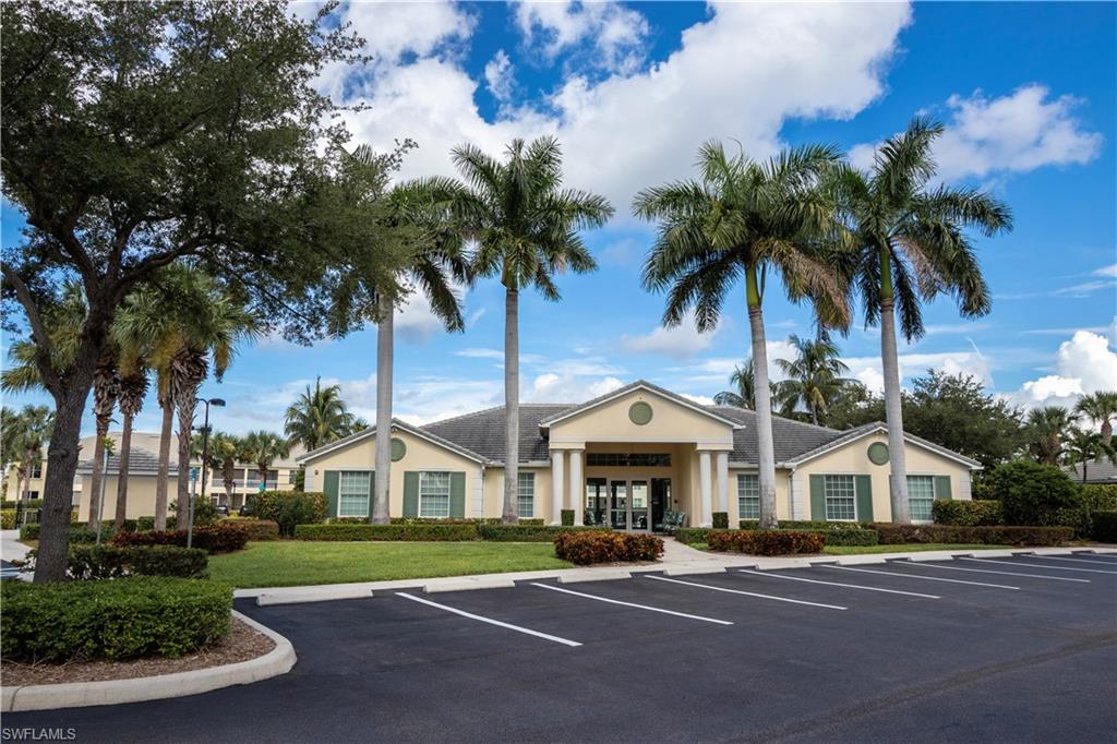 Building exterior featuring a gabled roofline, decorative window shutters, and mature palm trees