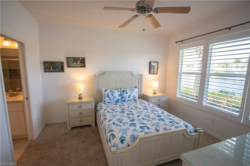 Carpeted room featuring a ceiling fan, two windows with plantation shutters, and a built-in vanity with a sink