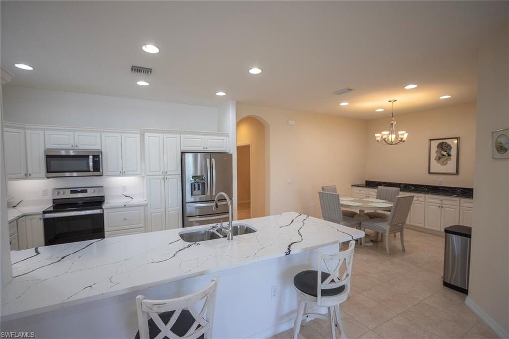Kitchen featuring white cabinetry, stainless steel appliances, and a kitchen island with stone countertops