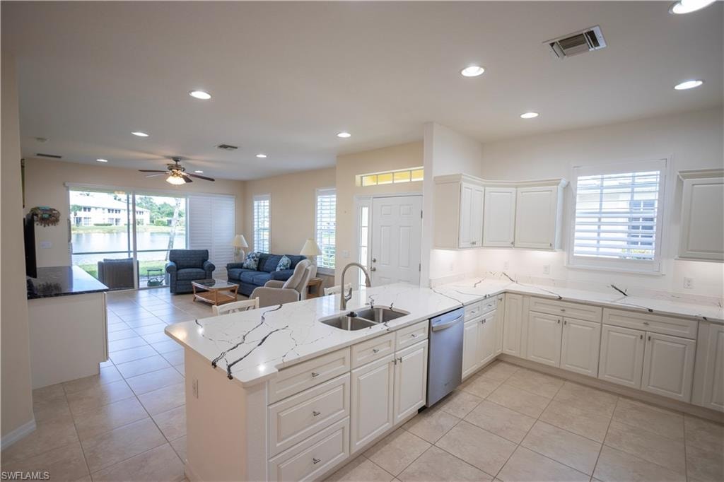 Modern kitchen with white cabinetry, stainless steel dishwasher, and a center island featuring a double-basin sink