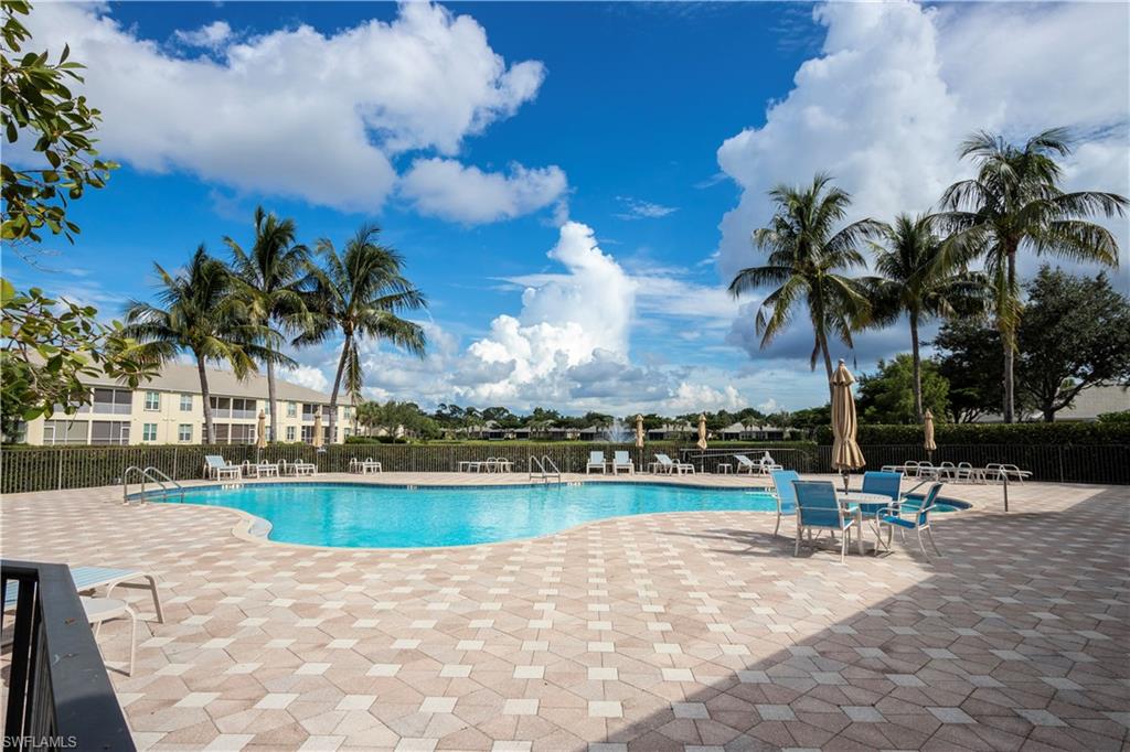 Expansive pool deck with patterned pavers, large swimming pool, and multiple palm trees