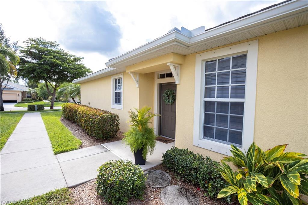 Stucco exterior with white trim, covered entryway, and front door with transom window
