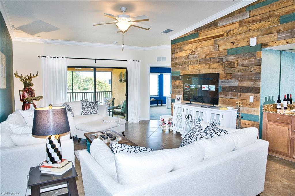 Wood accent wall, ceiling fan, crown molding, tile flooring, built-in bar with stone countertop